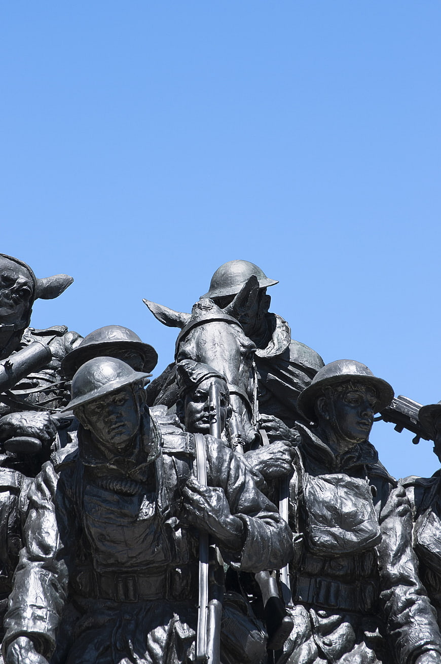 Bronze war memorial statue of soldiers and horses against blue sky
