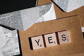 Scrabble tiles spelling YES on brown paper background