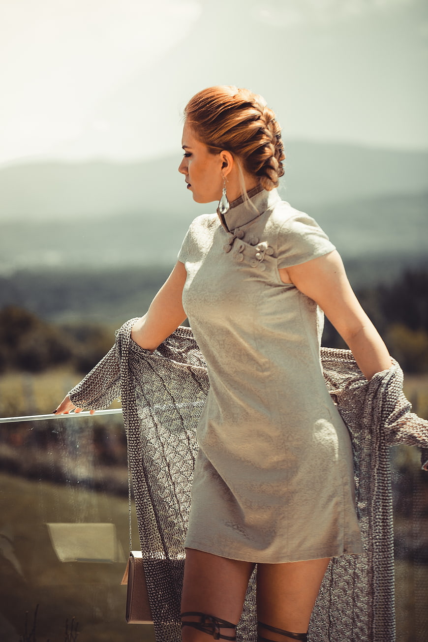 Fashionable woman in grey dress with braided hair on balcony