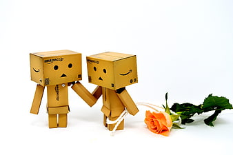 Two cardboard box characters holding hands with a rose
