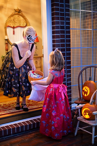 Woman in Halloween Mask Giving Candy to Little Girl