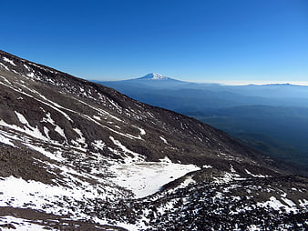 Snowy Rocky Mountain Slope with Distant Peak