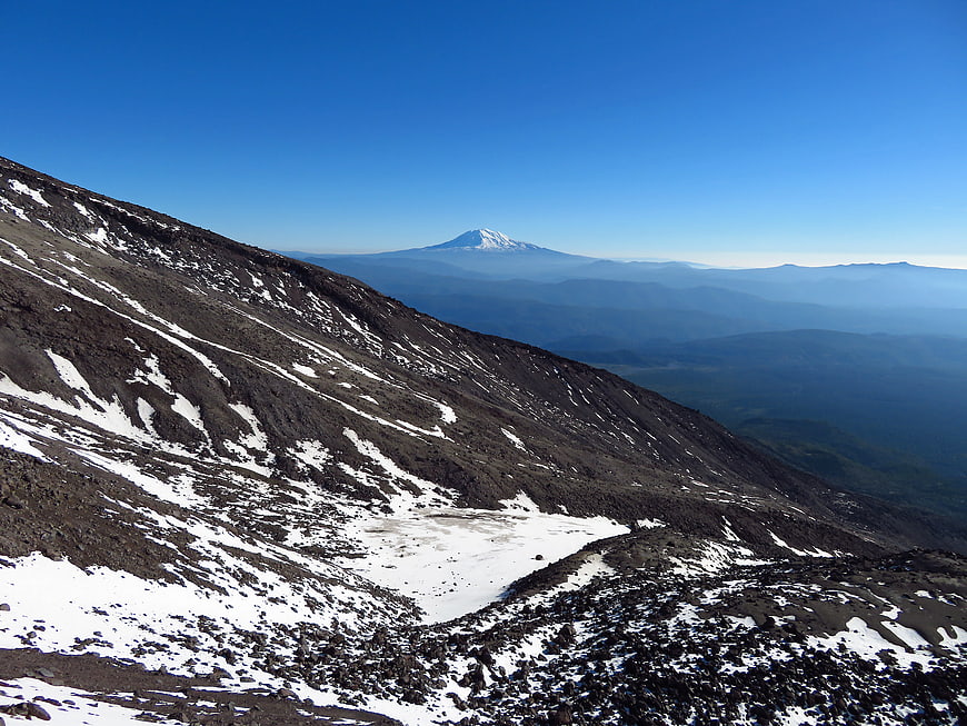 Snowy Rocky Mountain Slope with Distant Peak