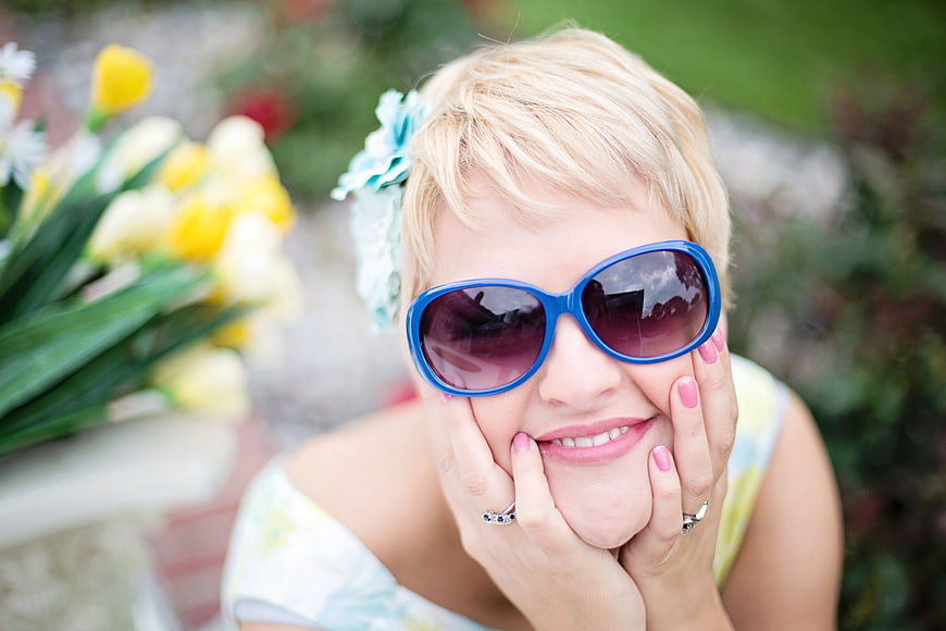 Happy blonde woman with blue sunglasses and spring flowers
