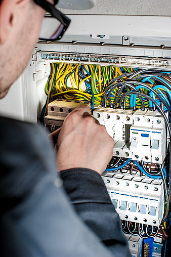 Electrician working on electrical panel with wires