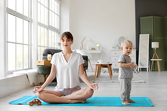 Mother meditating with toddler on yoga mat at home