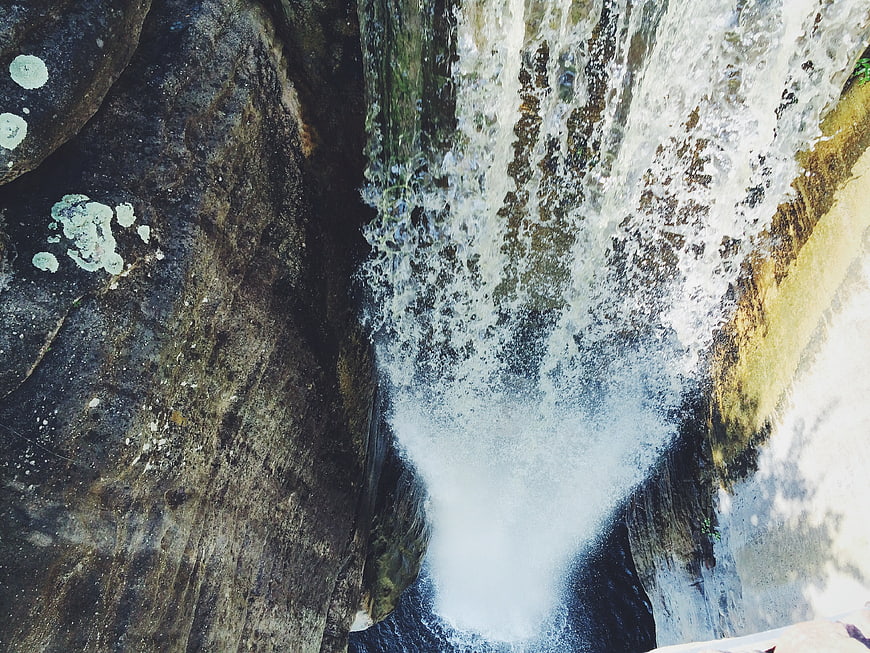 Top-down view of rushing waterfall crashing into rocky pool