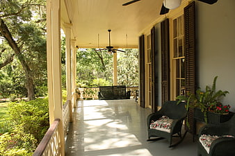 Southern Plantation Porch With Wicker Chairs And Lush Green Garden