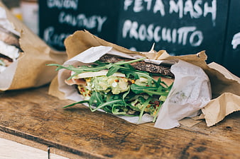 Fresh avocado sandwich with arugula on rustic wooden table