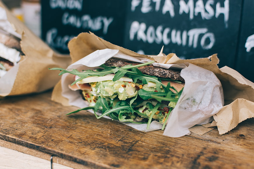 Fresh avocado sandwich with arugula on rustic wooden table
