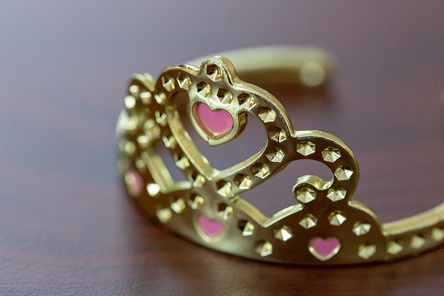Gold Princess Crown with Pink Hearts on Wooden Table