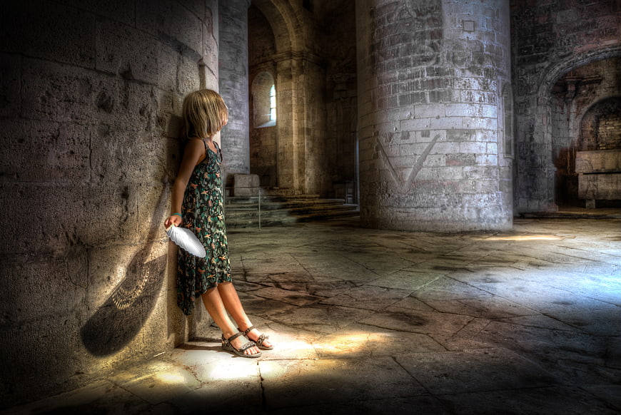Young girl holding white feather in ancient stone crypt