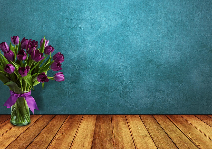 Purple Tulips in Glass Vase on Wooden Table with Blue Wall
