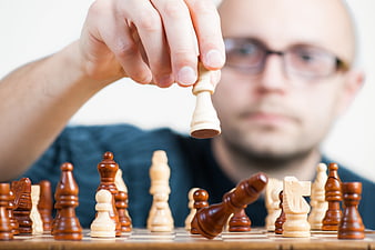 Man playing chess holding a pawn piece