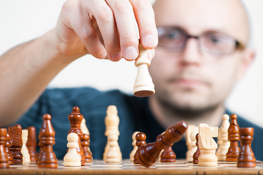 Man playing chess holding a pawn piece