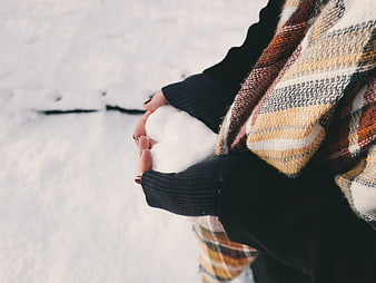 Woman holding snow heart in winter scarf