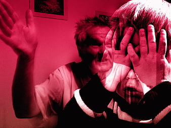 Red tinted image of child covering face from angry man
