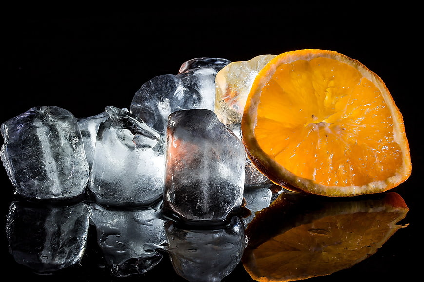 Fresh Orange Slice with Ice Cubes on Black Background
