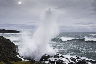 Powerful Ocean Wave Crashing Against Rocky Coastal Cliff