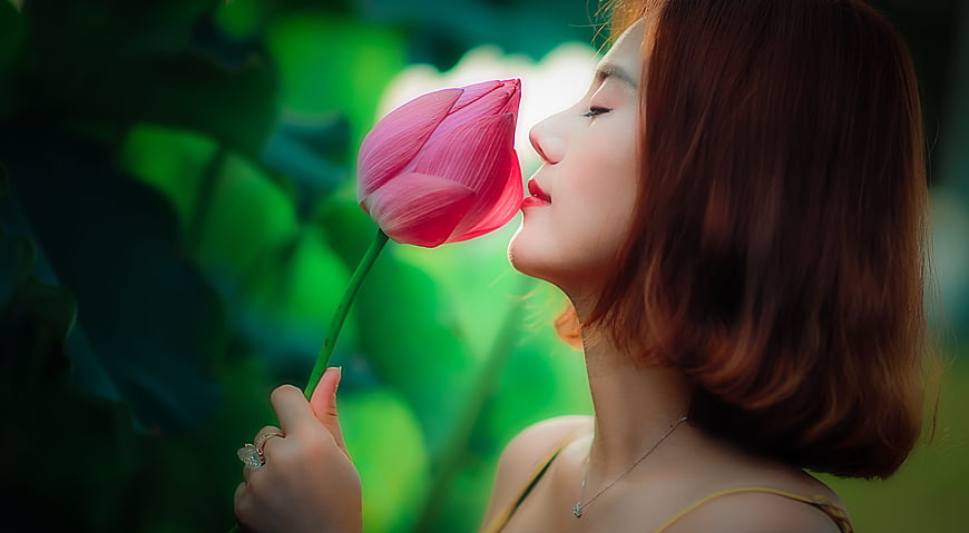 Young Asian Woman Smelling Pink Lotus Flower