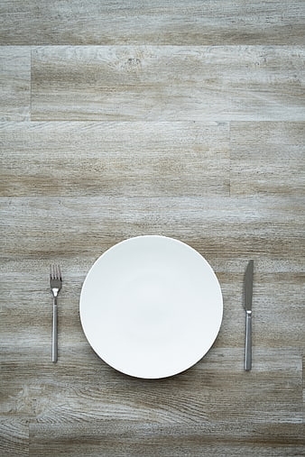 Minimalist white plate and silverware on rustic wooden table