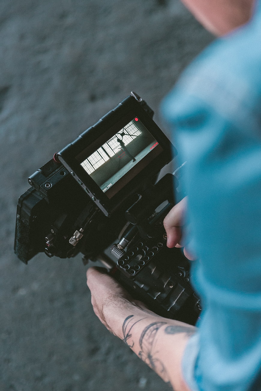 Cinematographer holding professional video camera with tattoo