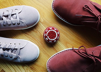 Two pairs of sneakers and a hacky sack on wooden floor