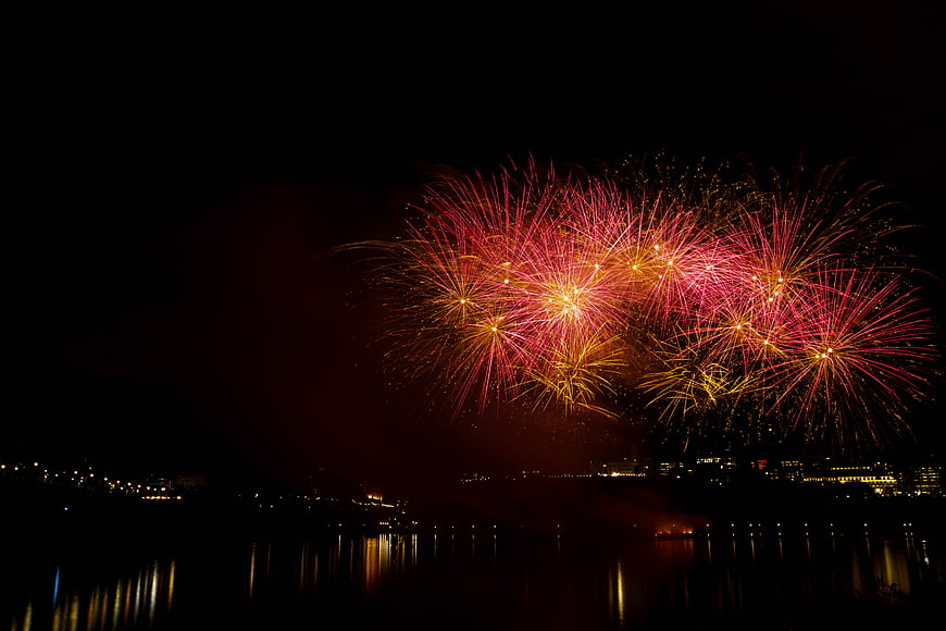 Vibrant red and gold fireworks exploding over a city skyline at night