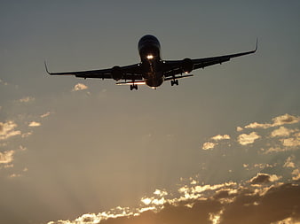 Silhouette of Airplane Landing at Sunset