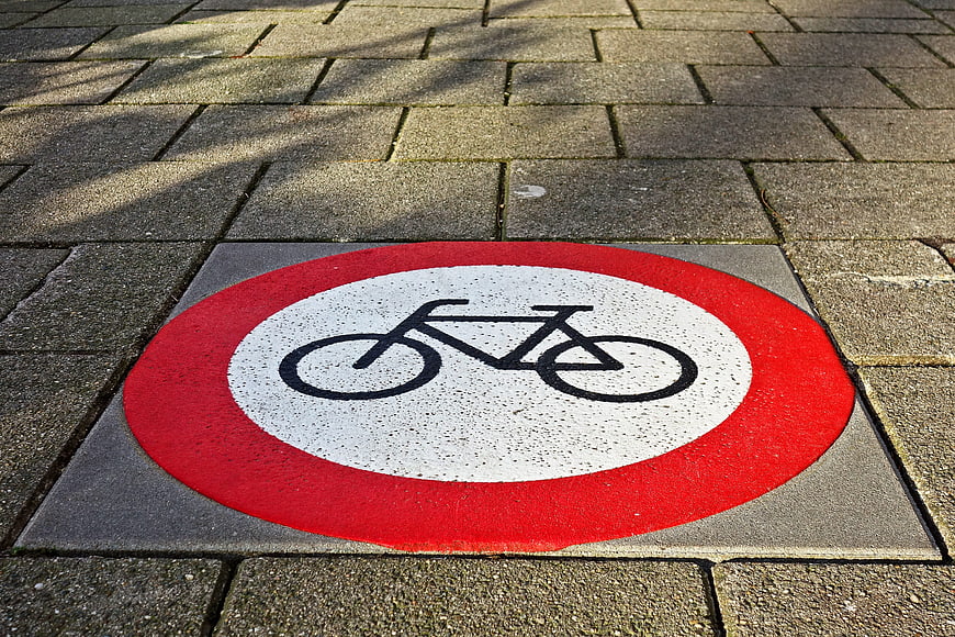 Red and white bicycle prohibition sign on pavement