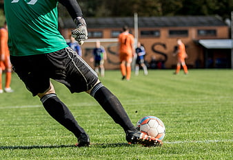 Soccer Goalkeeper Kicking Ball On Green Grass Pitch