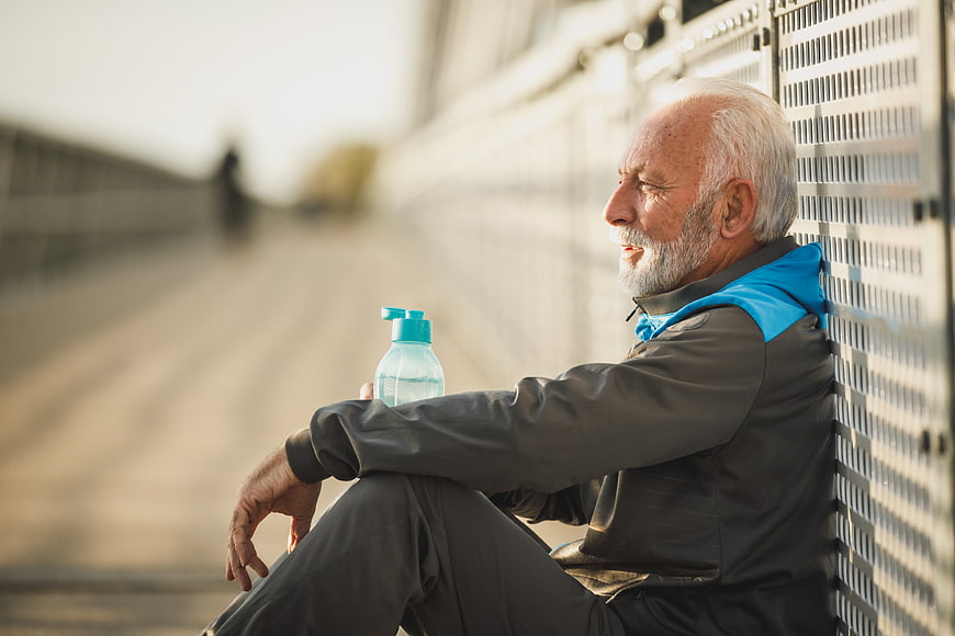 Senior man resting after workout with water bottle