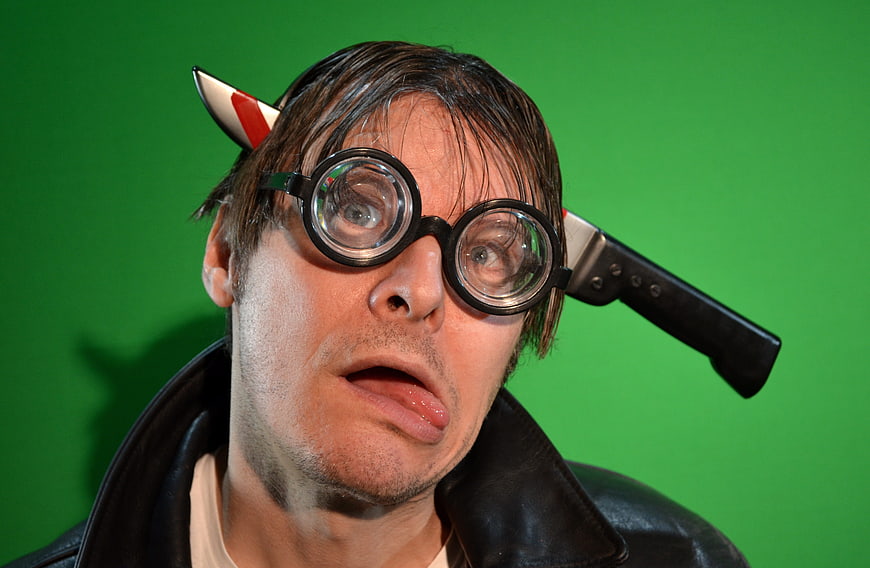 Man with knife in head and goggles on green screen