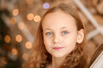 Close-up portrait of a young girl with blue eyes and bokeh lights