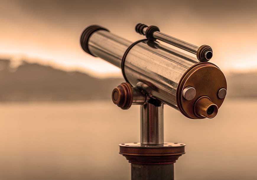 Vintage brass telescope on pier at sunset