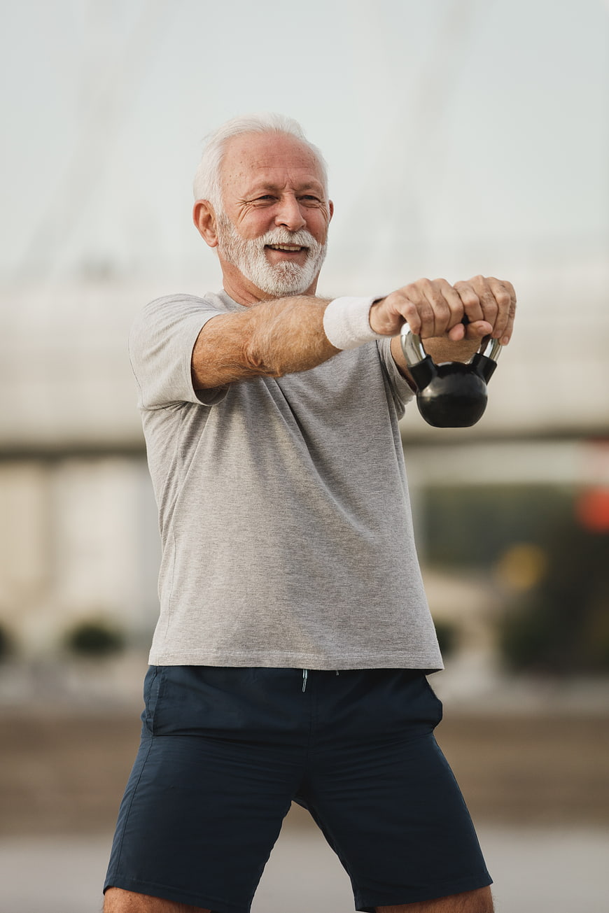 Senior man exercising with kettlebell outdoors
