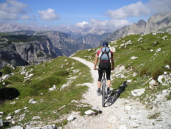 Cyclist riding mountain bike on alpine trail with scenic view