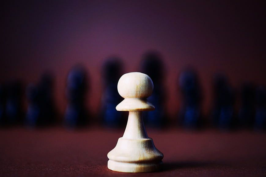 White Chess Pawn Facing Blurred Black Pieces