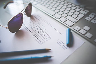 UX Design Sketches with Keyboard and Sunglasses on Desk