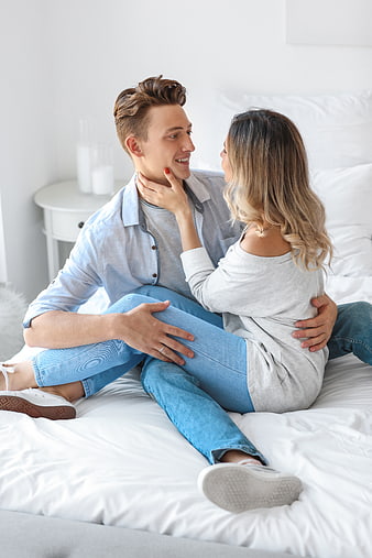 Happy young couple sitting on bed sharing intimate moment