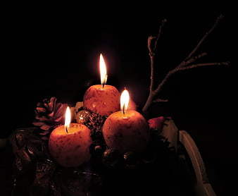 Advent candles with pinecones and branches on dark background