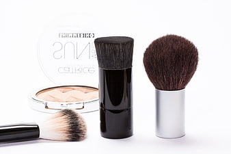 Professional makeup brushes and shimmering powder on white background