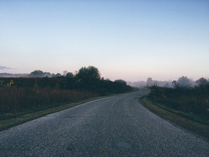 Foggy rural road winding through misty morning landscape
