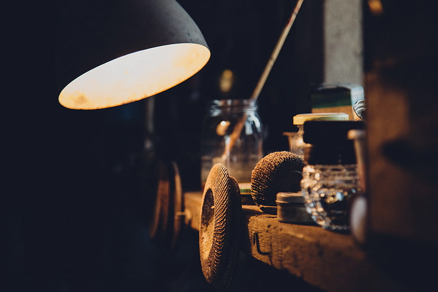 Vintage desk lamp illuminating wooden workspace with tools