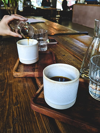 Pouring Coffee into Ceramic Cup on Wooden Table