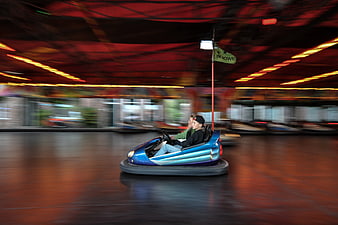 Two boys driving a blue bumper car in an indoor amusement park