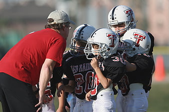 Youth Football Team Huddle With Coach On Field