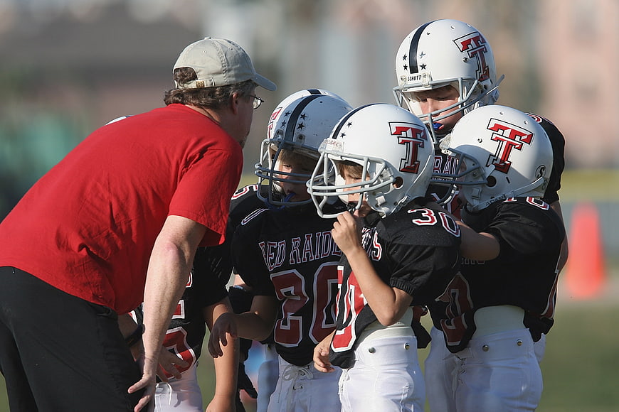 Youth Football Team Huddle With Coach On Field