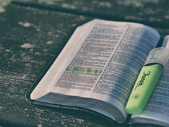 Open Bible with Green Highlighter on Textured Surface