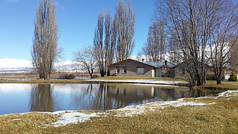 Rural house with pond and snow-capped mountains in spring